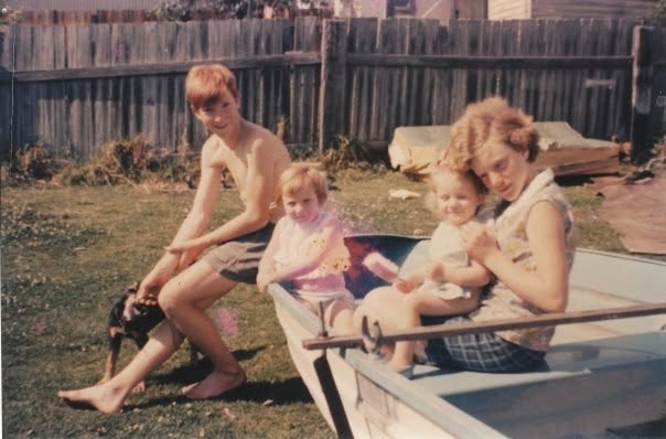 Anne as a baby in the backyard, held in a boat with her family